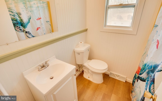 bathroom with visible vents, toilet, curtained shower, wood finished floors, and vanity