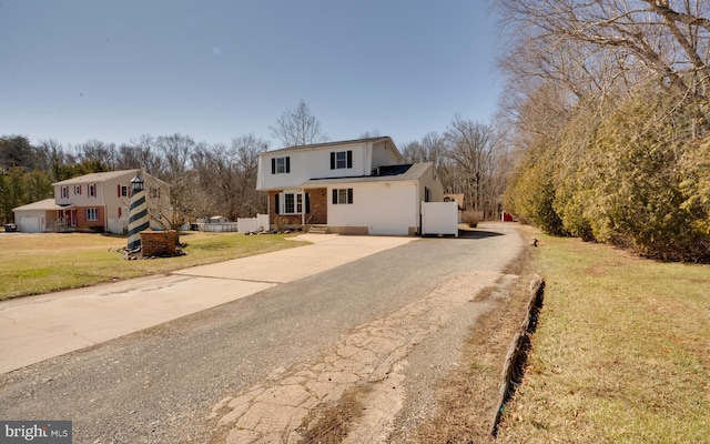 view of front of property featuring brick siding, a front yard, and driveway