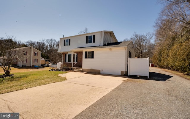 rear view of property with a lawn, brick siding, and driveway