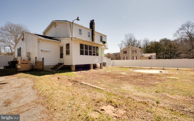 rear view of property featuring entry steps, fence, and a chimney