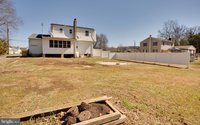 rear view of property with a vegetable garden, fence, a lawn, and a chimney