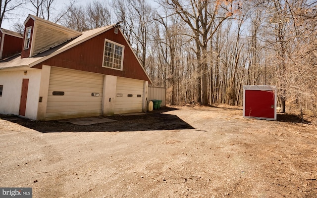 view of side of home featuring a garage, driveway, and an outdoor structure