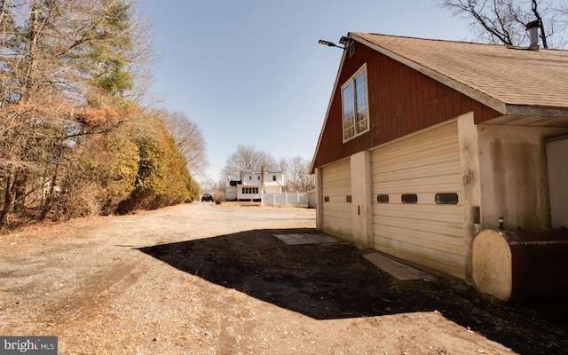 view of property exterior with a garage, an outdoor structure, and a shingled roof