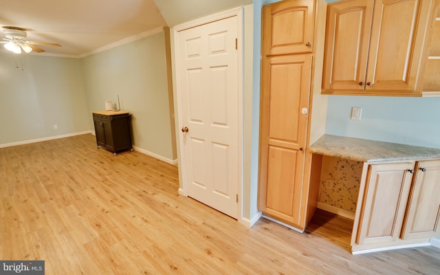 kitchen featuring light stone counters, baseboards, light wood-style flooring, built in desk, and crown molding