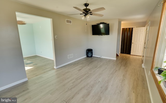 unfurnished living room featuring light wood-type flooring, visible vents, baseboards, and ceiling fan