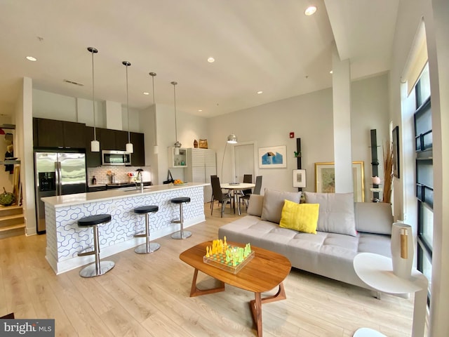 living area featuring a high ceiling, recessed lighting, and light wood finished floors