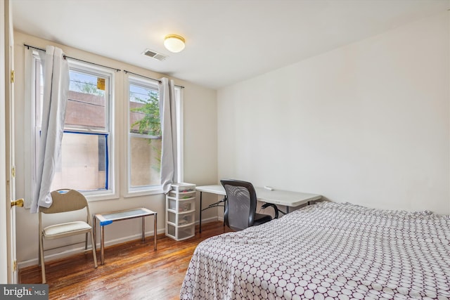 bedroom with wood finished floors, visible vents, and baseboards