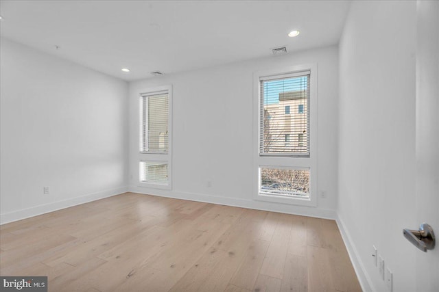 empty room featuring light wood-type flooring, visible vents, plenty of natural light, and baseboards