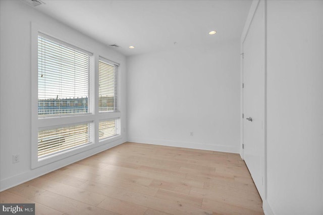 empty room featuring recessed lighting, light wood-type flooring, baseboards, and visible vents