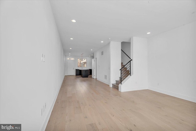 unfurnished living room with stairway, recessed lighting, light wood-style flooring, and baseboards