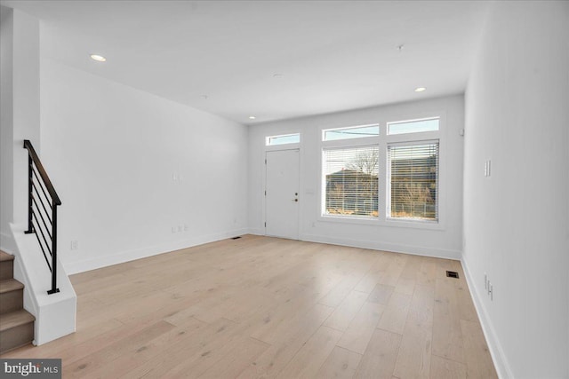 interior space featuring stairs, light wood-style floors, and baseboards