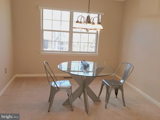 carpeted dining space with a notable chandelier and baseboards