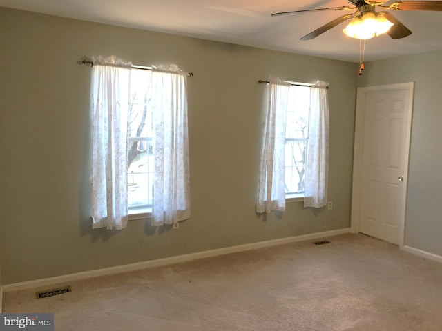 carpeted spare room featuring baseboards, visible vents, and a wealth of natural light