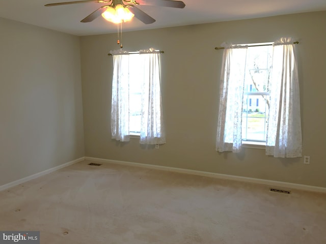 carpeted spare room featuring visible vents, baseboards, and a ceiling fan