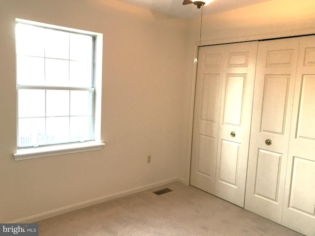 unfurnished bedroom featuring visible vents, baseboards, light colored carpet, and a closet