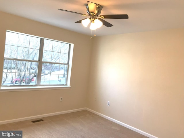 empty room with visible vents, light colored carpet, baseboards, and ceiling fan