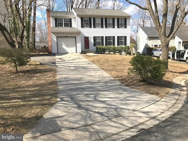 colonial home featuring a chimney and concrete driveway