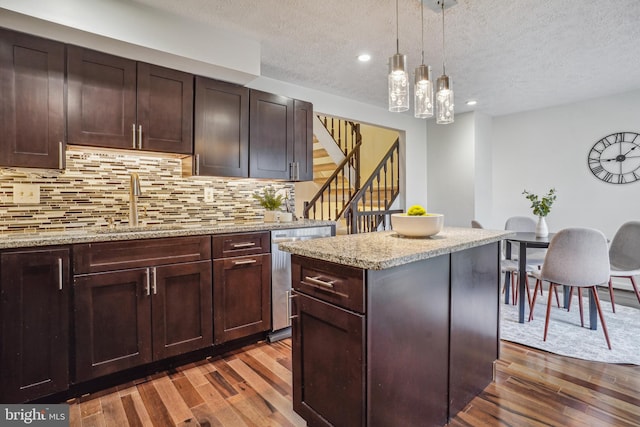 kitchen featuring a kitchen island, dark wood-style flooring, decorative backsplash, stainless steel dishwasher, and decorative light fixtures