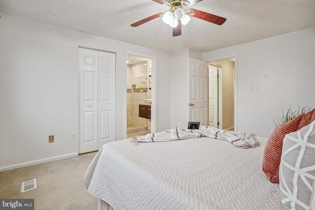 bedroom with visible vents, light carpet, a textured ceiling, a closet, and baseboards