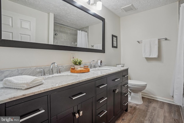 bathroom featuring a sink, visible vents, toilet, and wood finished floors