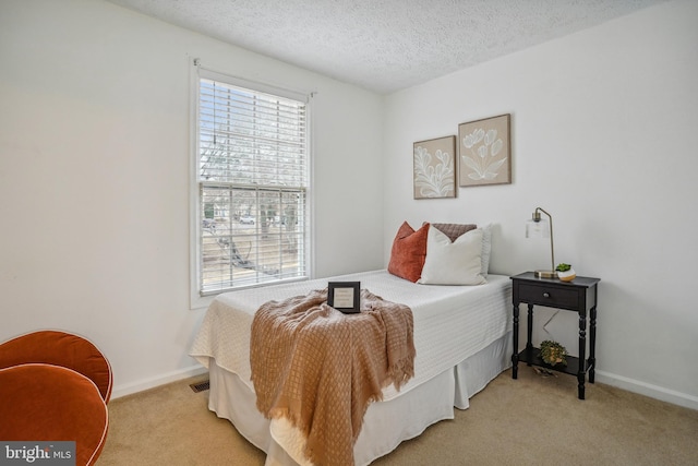 bedroom with light carpet, a textured ceiling, and baseboards