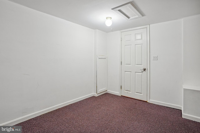 unfurnished room featuring attic access, baseboards, and dark carpet