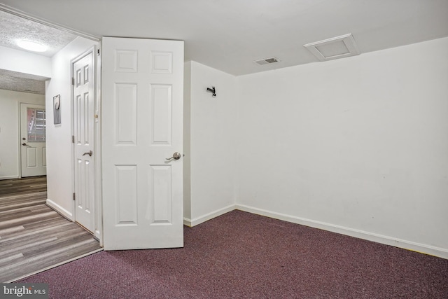 carpeted spare room featuring visible vents, baseboards, a textured ceiling, and attic access