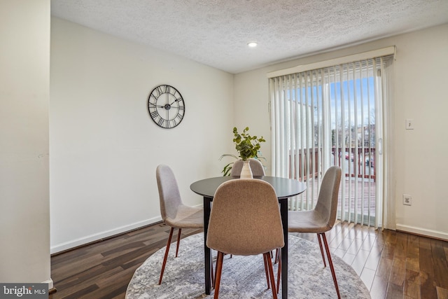 dining area with a textured ceiling, baseboards, and wood finished floors