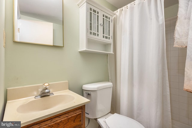 full bath featuring tiled shower, toilet, and vanity