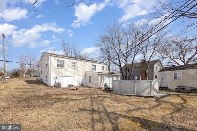 back of house with an outdoor pool and a lawn