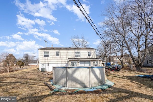 back of house featuring an outdoor pool, central AC, and fence