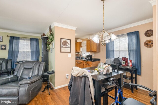 dining space with an inviting chandelier, light wood-style flooring, crown molding, and a wealth of natural light