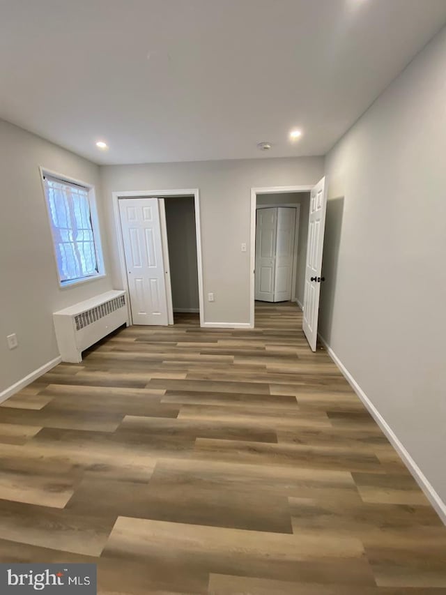 unfurnished bedroom with recessed lighting, radiator heating unit, baseboards, and wood finished floors