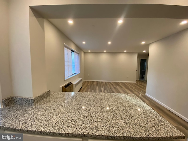 kitchen with light stone counters, recessed lighting, baseboards, and wood finished floors