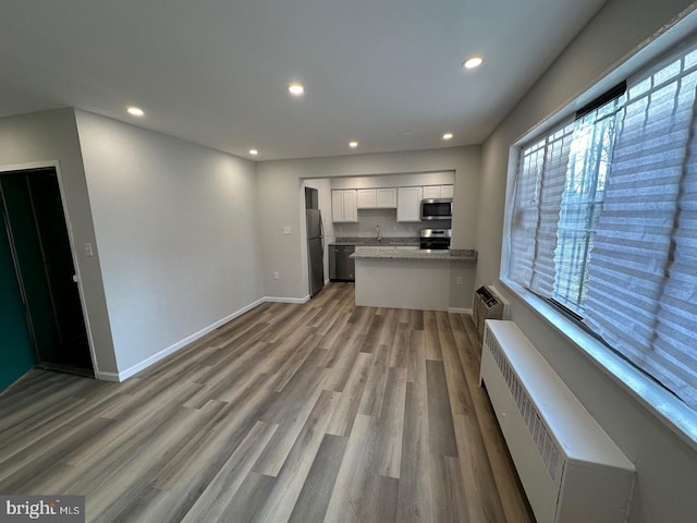 kitchen featuring wood finished floors, white cabinetry, recessed lighting, appliances with stainless steel finishes, and baseboards