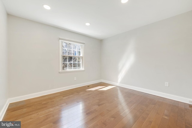 empty room featuring recessed lighting, baseboards, and wood-type flooring