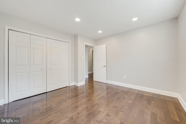 unfurnished bedroom featuring recessed lighting, a closet, baseboards, and wood finished floors