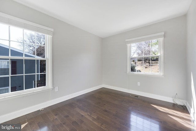 unfurnished room with visible vents, baseboards, and dark wood-type flooring