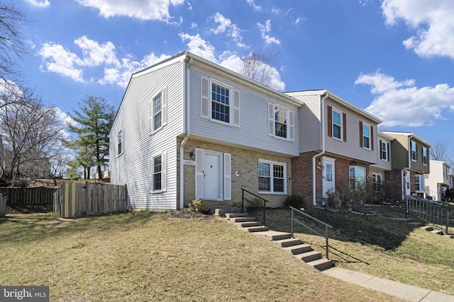 view of front of home featuring a front yard, fence, and brick siding