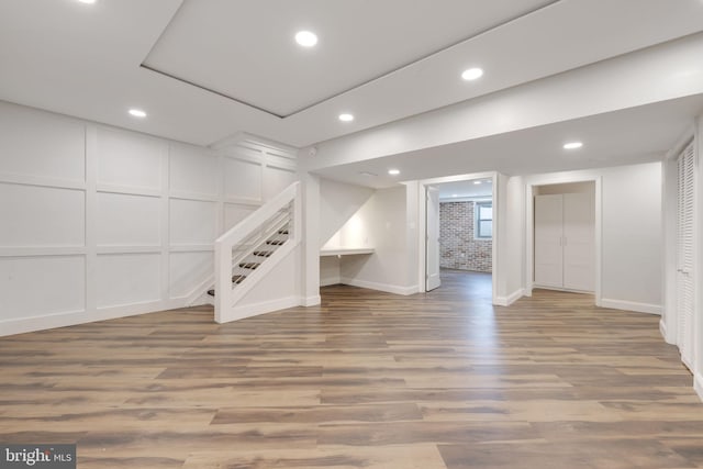 finished basement with recessed lighting, wood finished floors, and a decorative wall