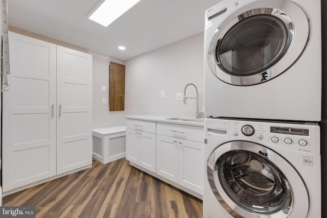 laundry room with dark wood-type flooring, a sink, recessed lighting, cabinet space, and stacked washer / dryer