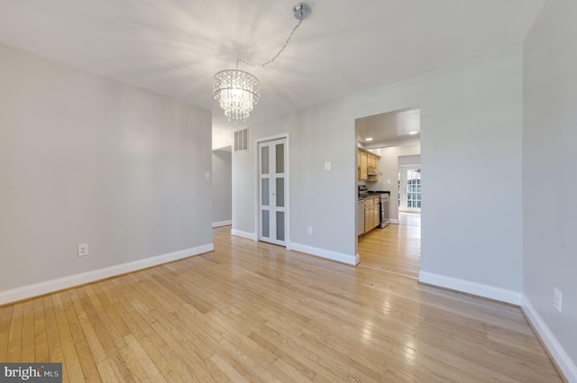 spare room featuring visible vents, an inviting chandelier, baseboards, and light wood-style floors