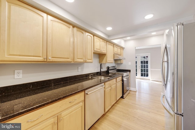 kitchen featuring light wood finished floors, a sink, light brown cabinetry, stainless steel appliances, and under cabinet range hood