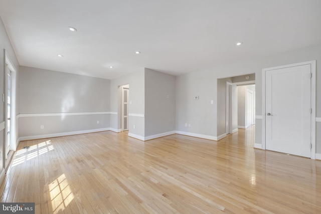 empty room featuring recessed lighting, baseboards, and light wood finished floors