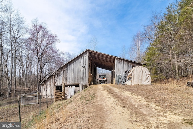 view of pole building with a carport, fence, and driveway