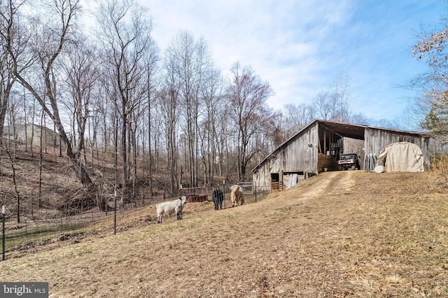 view of side of property featuring an outbuilding, dirt driveway, a rural view, an outdoor structure, and a carport