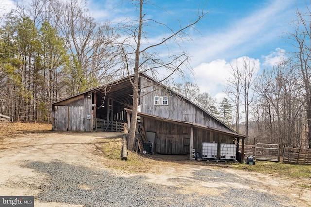 view of home's exterior with a detached garage, an outbuilding, driveway, and fence