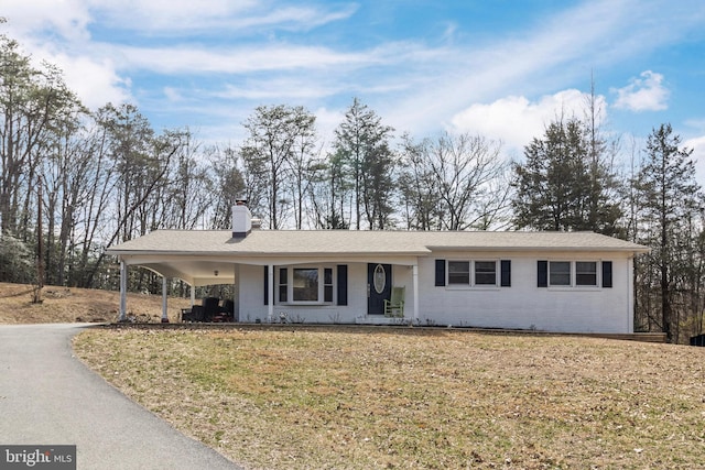 ranch-style house with aphalt driveway, a chimney, a front yard, and a carport