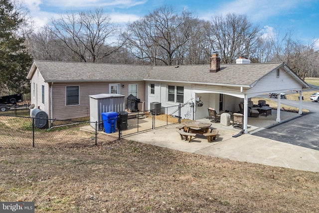 rear view of house with a shingled roof, fence, central air condition unit, a chimney, and a patio