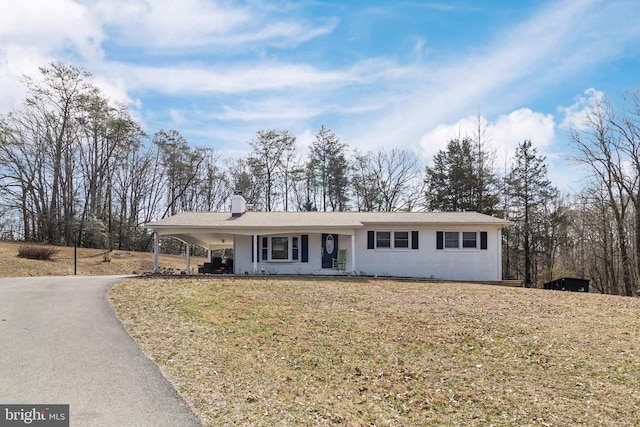 single story home with an attached carport, a front lawn, driveway, and a chimney